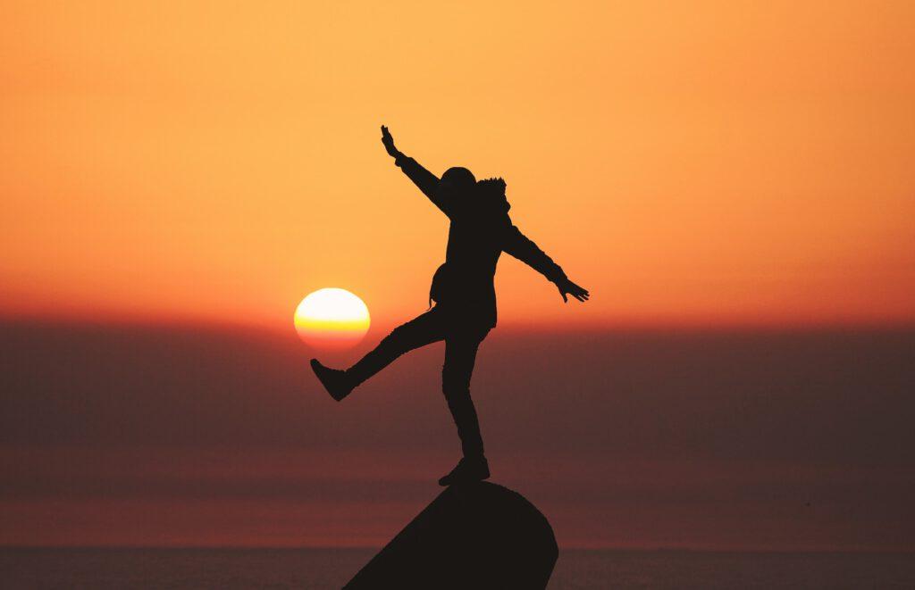 Photo of a man balancing on a stone with only one foot, illustrates a state of balance, which is very preached by Ayurveda, through the balance of its doshas.