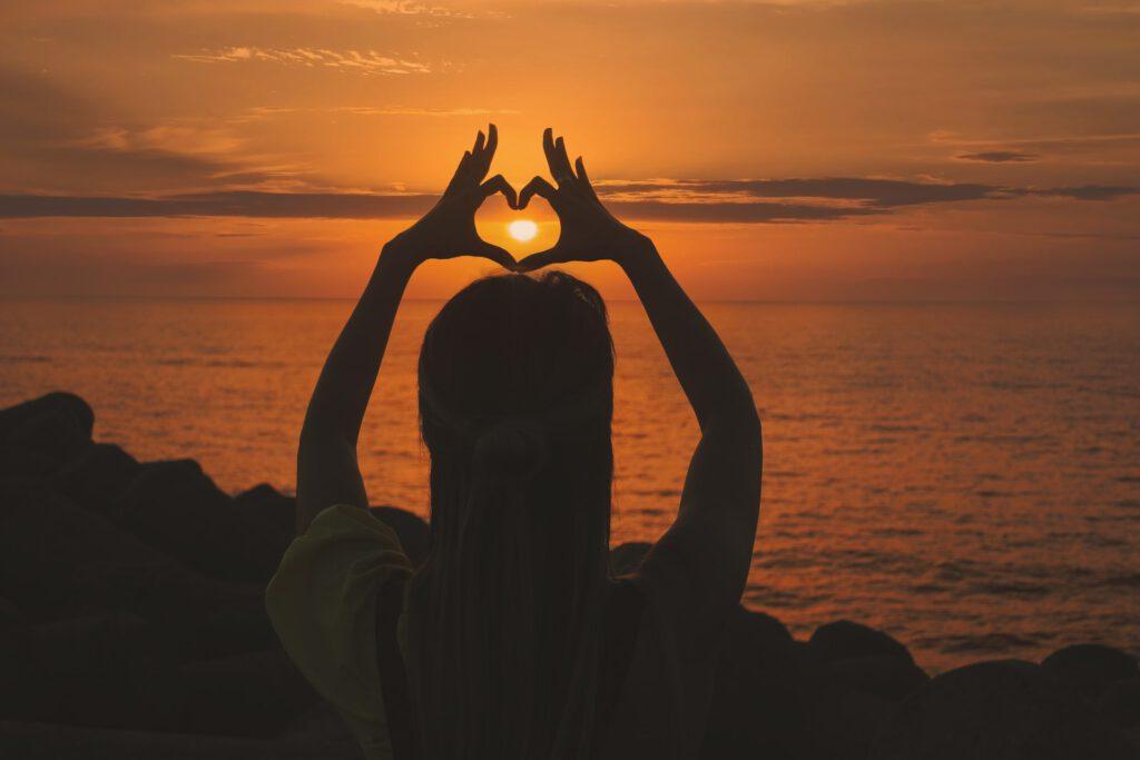 Image of a woman making the heart gesture at sunset. It is very important to keep your heart healthy and for that, use the knowledge of ayurveda.