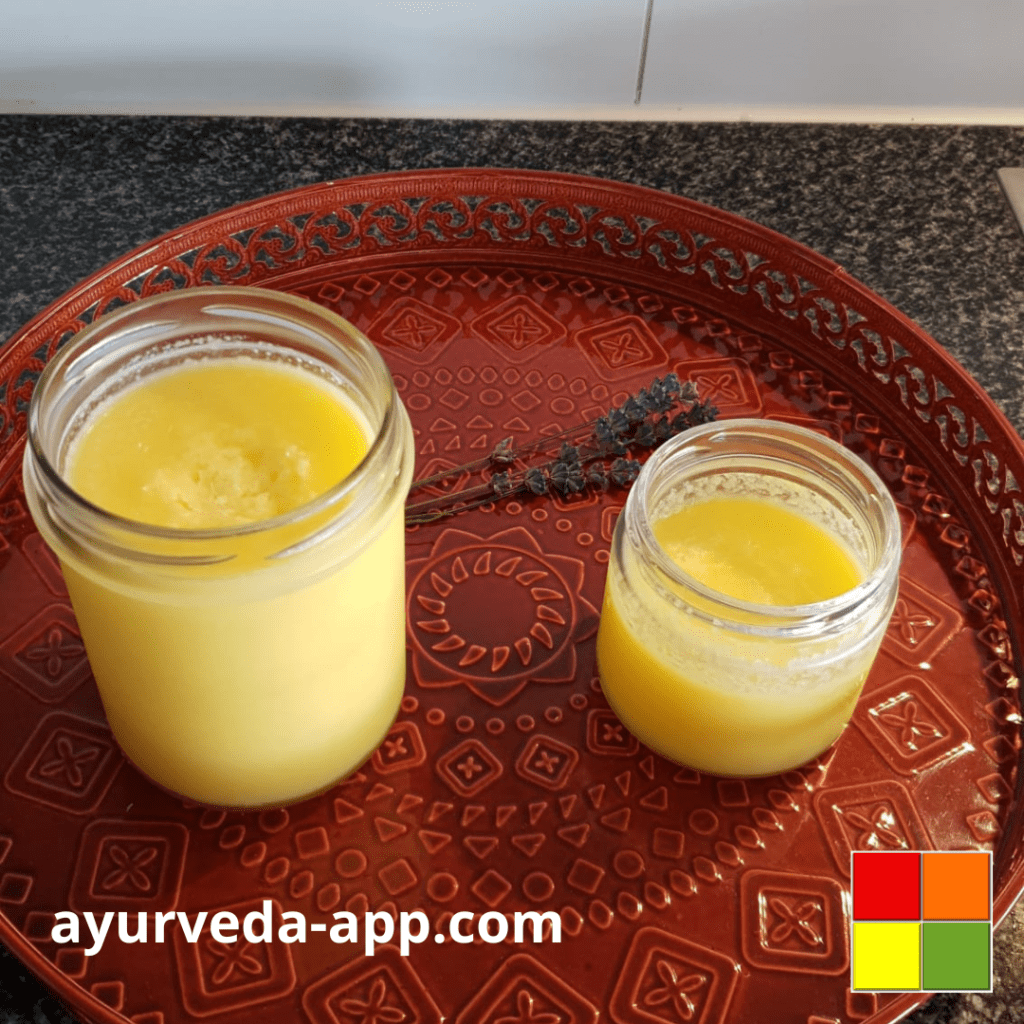 Photo of two glass jars full of Ghee, on top of a decorated red tray.