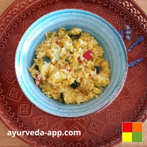 Photo of recipe Kitchari (European version) served in a blue bowl with brown edges. The bowl is on top of a decorated round red tray.