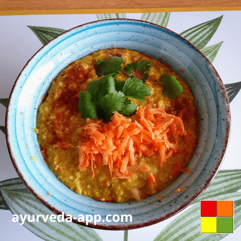 Photo of a brown-rimmed blue bowl of Spicy barley porridge with shredded carrots and herbs for garnish.