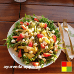 Photo of a plate of Asparagus Potato Salad, with strawberries and decorated with edible flowers. Beside the plate is a fork and knife on top of a decorated napkin.