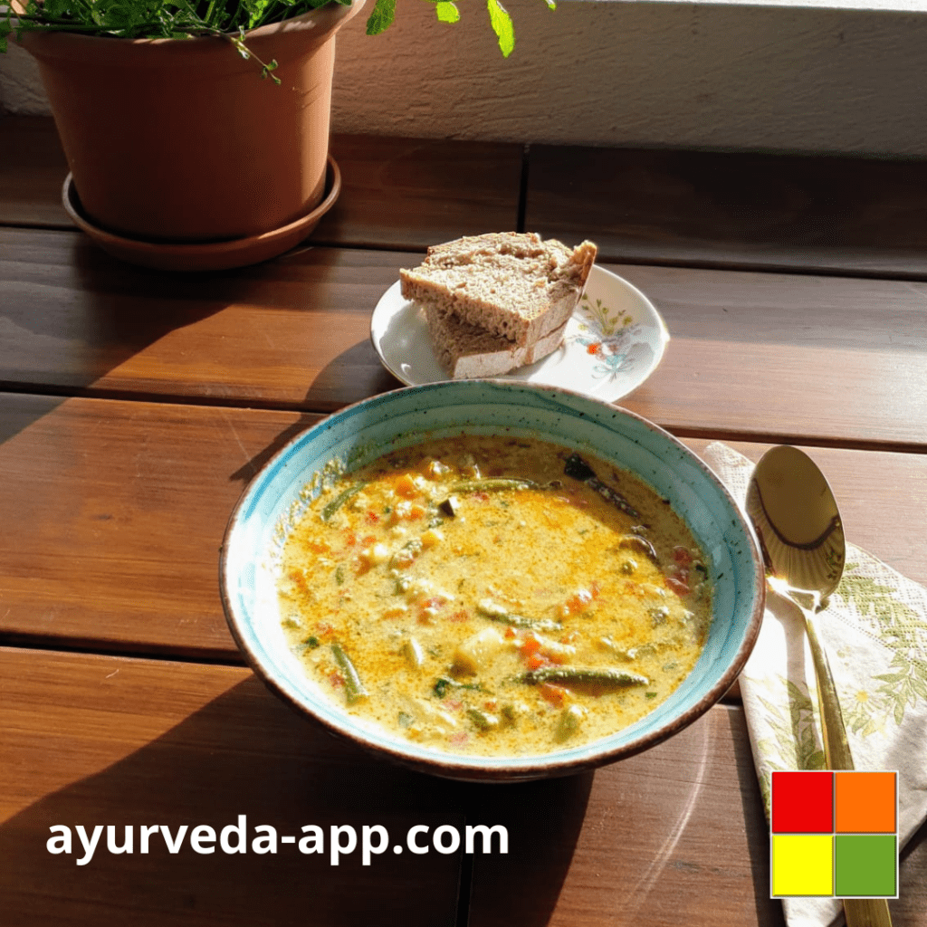 Summer vegetable soup. Behind the bowl is a plate with two slices of bread, a great accompaniment to soups. Next to the bowl is a decorated napkin with a spoon.