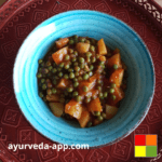 Photo of potatoes-peas stew recipe in a blue bowl on top of a decorated red tray.