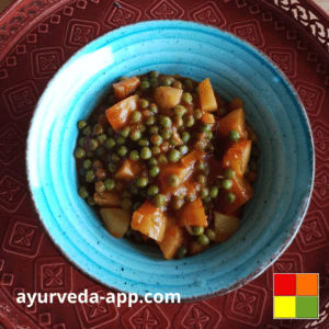 Photo of potatoes-peas stew recipe in a blue bowl on top of a decorated red tray.