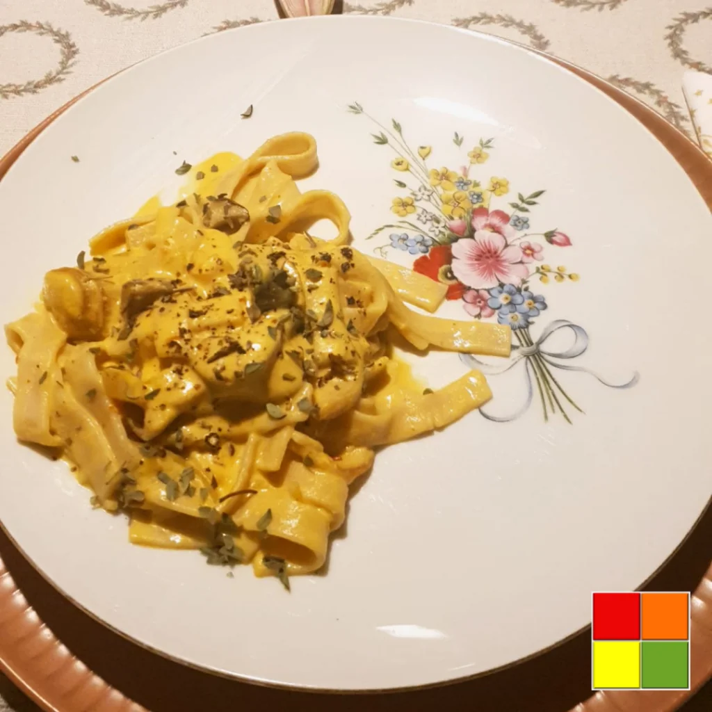 Foto von veganen cremigen Tagliatelle auf einem weißen, mit Blumen dekorierten Teller