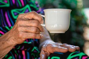 Photo of an elderly person's hand holding a cup of tea. Ayurveda offers a holistic approach to the treatment of arthritis, an inflammatory joint disease that causes pain, swelling and restricted movement.