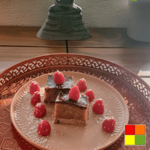 Photo of Peanut Butter Date Squares on a brown plate decorated with raspberries and coconut flakes