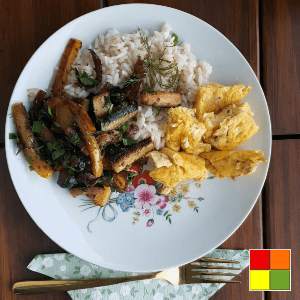 Photo of Vegetables with eggs and rice on a white plate with flowery details. Below the plate is a golden fork on top of a green flowered napkin.